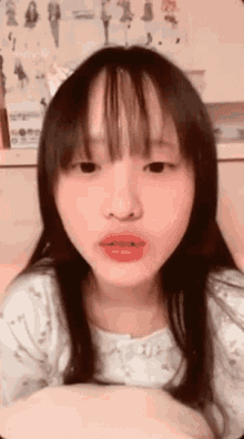 a young girl with long hair and bangs is making a face .