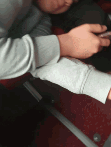 a person wearing a grey sweatshirt is using a phone
