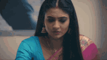 a woman in a blue and pink sari is sitting at a table .