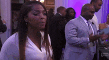 a woman in a white shirt and a man in a suit are standing in a crowd of people .