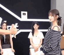 a woman in a striped shirt is giving a thumbs up to another woman