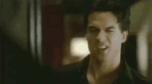 a man in a black shirt is making a funny face in a room .