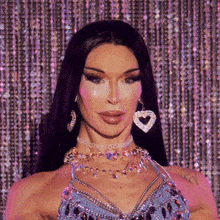 a woman wearing a necklace and earrings with a heart shaped earring