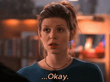 a woman in a blue shirt says " okay " in yellow letters