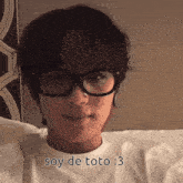 a young man wearing glasses and a white shirt says soy de toto
