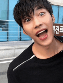 a young man is making a funny face in front of a sign that says ' korean ' on it