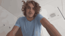 a man with long curly hair is wearing a light blue shirt