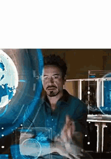 a man is sitting in front of a screen with a globe behind him .