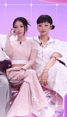 two women are sitting next to each other on a couch .