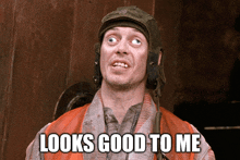a man wearing a helmet and an orange vest has the words " looks good to me " above him