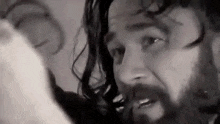 a black and white photo of a man with a beard looking at something .