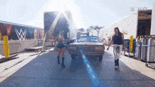 a man and a woman are standing in front of a car with a wwe logo on it
