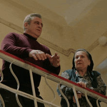 a man and a woman are standing on a staircase looking down
