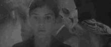 a black and white photo of a man with a skeleton mask behind him .