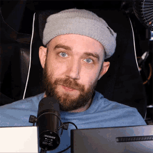 a man with a beard wearing a gray beanie and a shure microphone