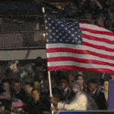 a group of people holding an american flag in a stadium