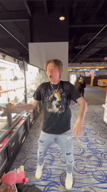 a man in a black t-shirt is standing in a hallway .