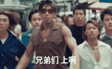 a group of men are walking down a street and one of them has chinese writing on his shirt .