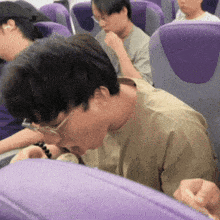 a man with glasses is sitting in a purple seat
