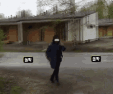 a person wearing a mask is walking down a street in front of a building with chinese characters on it