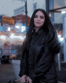a woman in a black leather jacket is standing in front of a building with a sign that says ' subway ' on it