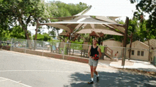 a man walking in front of a playground with an umbrella that says ' tnt ' on it