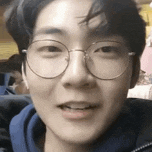 a close up of a young man wearing glasses and a blue jacket .
