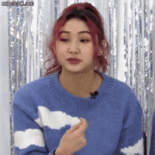 a woman with red hair is wearing a blue and white sweater with clouds on it .