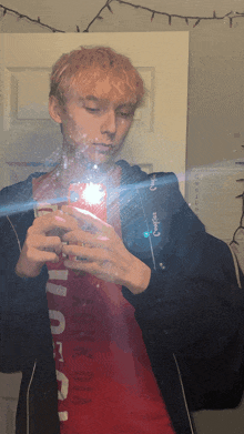 a man taking a picture of himself in a mirror wearing a red shirt that says ' brooklyn ' on it