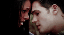 a man and a woman are looking into each other 's eyes and touching their foreheads .