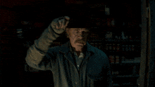 an older man wearing a beanie stands in front of a shelf full of boxes and bottles