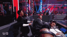a group of people sitting in a wrestling ring with a usa logo in the corner