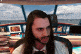 a man with long hair and a beard is sitting in front of a computer monitor