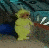 a yellow teletubbies doll is standing next to a blue and red object .