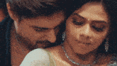 a man and a woman are hugging and the woman is wearing a diamond necklace