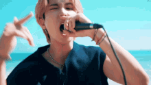 a man singing into a microphone on the beach