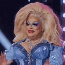 a drag queen is wearing a blue top and necklace