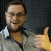 a man with a beard and glasses is giving a thumbs up sign .