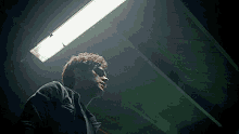 a man in a black jacket is looking up at a light