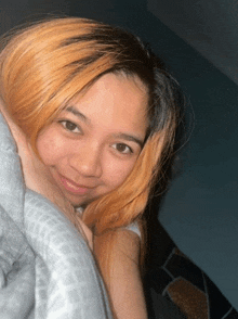 a young woman with blonde hair is smiling and laying on a bed