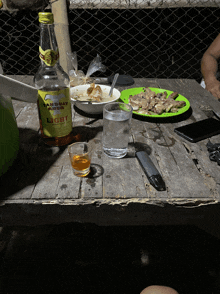 a bottle of sandway light sits on a wooden table next to a plate of food