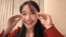 a young woman is making a funny face with her hands while smiling .