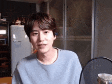 a young man in a blue sweater is sitting in front of a microphone .