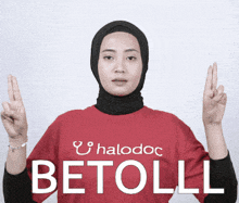 a woman wearing a red shirt that says halodoc betoll