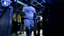 a man in a white t-shirt with the word justice on it stands in a dark room