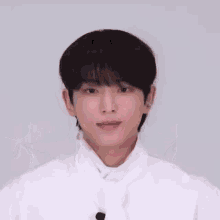a young man wearing a white shirt and tie is making a heart shape with his hands .