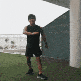 a man in a black tank top and black shorts is standing on a green field