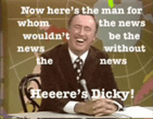 a man in a suit and tie is sitting at a desk with a microphone in front of him .