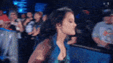 a woman with blue hair is standing in front of a crowd with the letters n and w on the screen