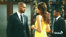 a man in a suit and tie is talking to a woman in a yellow dress .